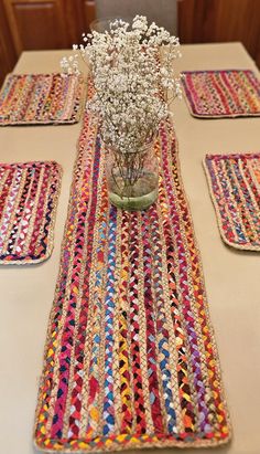 a vase filled with flowers sitting on top of a table covered in placemats