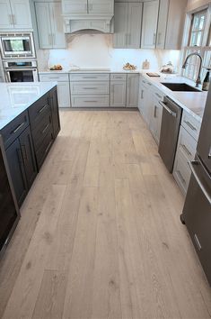 a large kitchen with white cabinets and wood flooring on the countertops, along with stainless steel appliances