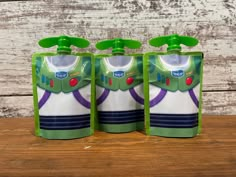 two green and white toy story book style toothbrush holders on a wooden table with wood planks in the background