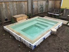 an empty swimming pool in the middle of a backyard with wooden fence and bench around it