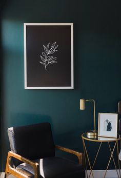 a living room with green walls and a black chair next to a gold side table