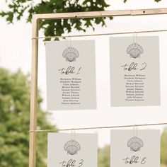 the table numbers are hanging from strings with seashells attached to them, along with other seating cards