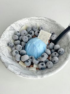 a bowl filled with blueberries and cake on top of a white tablecloth covered plate