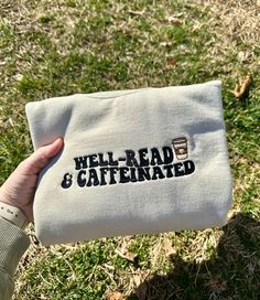 a person holding up a white towel with the words well read and caffeinated on it