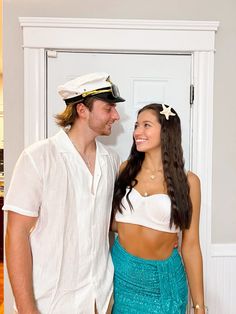 a man and woman are standing next to each other in front of a door wearing sailor's hats