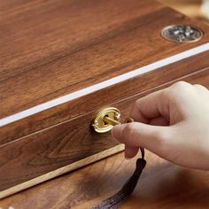 a person is opening a wooden box with a tassel on the top and bottom