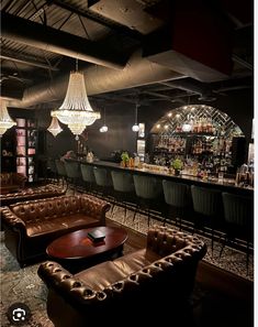 a dimly lit bar with leather couches and chandeliers