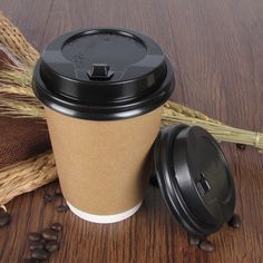 a coffee cup sitting on top of a wooden table next to some beans and straw