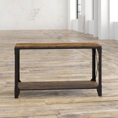 a wooden table sitting on top of a hard wood floor next to a white brick wall