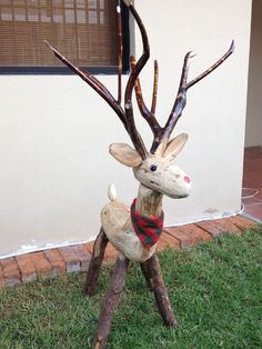 a statue of a deer with a scarf on it's head sitting in the grass