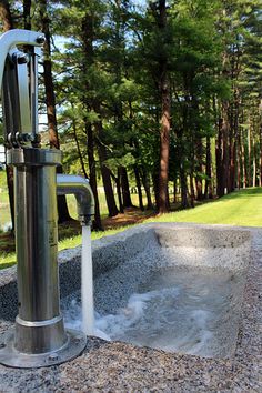 a faucet with water coming out of it in the middle of a park