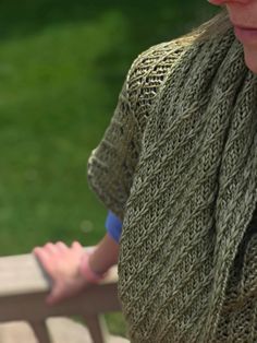 a woman is sitting on a bench wearing a sweater