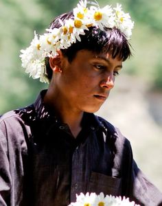 a woman with flowers in her hair holding a bouquet of daisies on her head