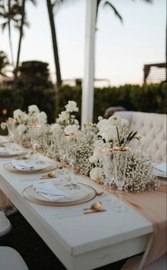 a long table with white flowers and place settings