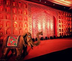 an elephant statue sitting on top of a red carpet next to a wall covered in lights