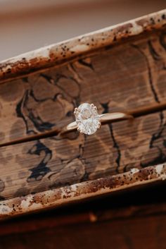 an engagement ring sitting on top of a wooden box with rusted wood in the background