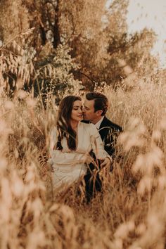 a man and woman are sitting in tall grass