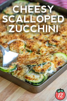 cheesy scalloped zucchini in a baking dish with a serving spoon