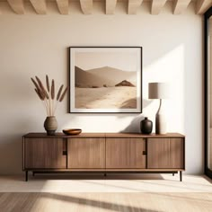 a living room with a large painting on the wall next to a wooden cabinet and lamp