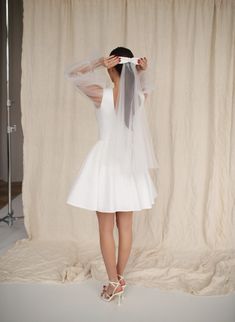 the back of a woman's wedding dress with a veil over her head and heels