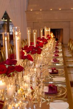 a long table is set with candles and red rose centerpieces for an elegant dinner