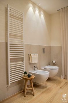 two white toilets sitting next to each other in a bathroom with wooden floors and walls