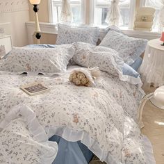 a bed with white and blue comforters in a bedroom next to a window,