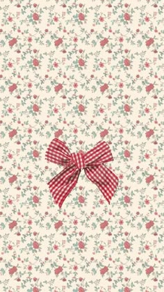 a red bow on top of a white wallpaper with small flowers and leaves in the background