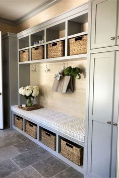 a white bench with baskets and flowers on it next to a wall mounted coat rack