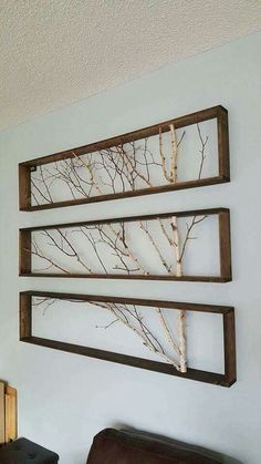 three wooden frames with branches hanging on the wall