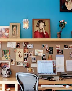 a desk with a laptop computer sitting on top of it next to a wall covered in pictures