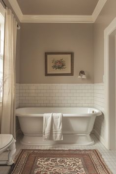 a white bath tub sitting under a window next to a rug on the bathroom floor