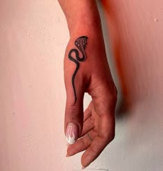 a woman's hand with a black and white tattoo on her left wrist, holding onto a pink wall