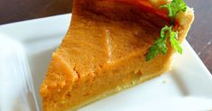 a slice of pumpkin pie on a white plate with a green garnish in the middle