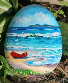 an egg painted to look like a boat on the beach