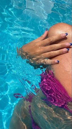 a woman in a pink swimsuit is floating in the water with her hands on her chest