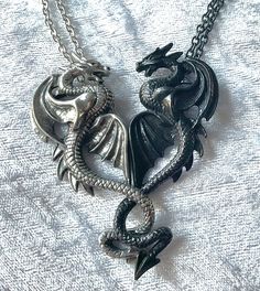 "Sweetheart Couples Necklace Consorts of darkness and partners in deviance collude and entwine with adamantine embrace, for an insight of oneness to belong to one another for eternity. An interlocking, separable, two-tone double necklace. Two pendants in one; symmetrical pewter dragons, one black and the other a silvery antiqued pewter, entwine and face each other to form a great heart shape. The two dragons are fastened together by hidden magnets and break apart when pulled, making two separate pendants on their own chains. On two separate trace chains, one black one silver, 18\" (46cm) long. Can be worn linked together or as two separate pendants. The pendants come with a velvet gift pouch. Made by Kiss of a red rose with help from Alchemy England 1977." Bff Necklaces For 2 Best Friends, Two Dragons, Dragon Wedding, Couples Necklace, Fairy Grunge Aesthetic, Dragon Heart, Princess Jewelry, Double Necklace, Bff Necklaces