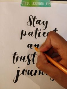 a person writing on a piece of paper that says stay patient and trust journaling