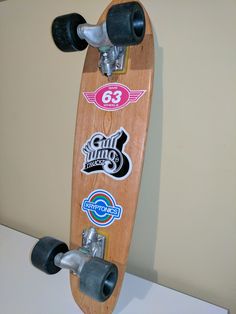 a skateboard with stickers on it hanging from the side of a white wall