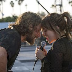 a man and woman singing into a microphone while standing next to each other on the street