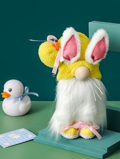 a stuffed animal bunny sitting on top of a green table next to a rubber duck