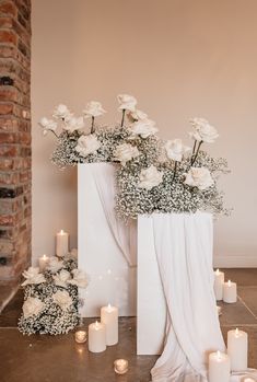 two white vases filled with flowers next to candles