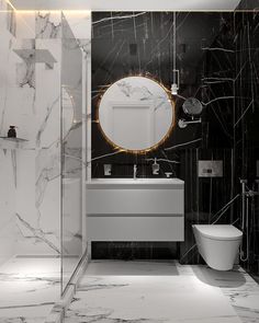 a bathroom with black and white marble walls, a round mirror over the bathtub