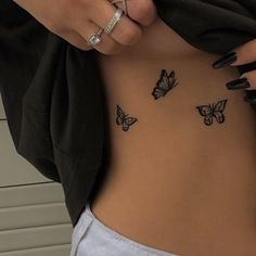 a woman's stomach with butterflies tattooed on the side and her hand holding onto it