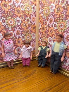 five dolls are lined up against a wall