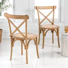 two wooden chairs sitting next to each other in front of a potted plant and window