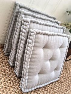 three pillows sitting on top of a carpeted floor