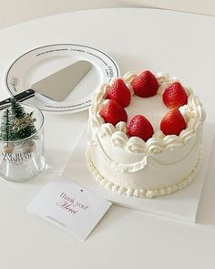 there is a cake with strawberries on it next to a knife and some cards