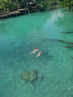 two people are swimming in the clear blue water