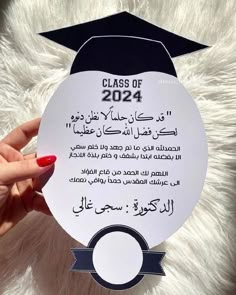 a person holding up a sign that says class of 202 with arabic writing on it